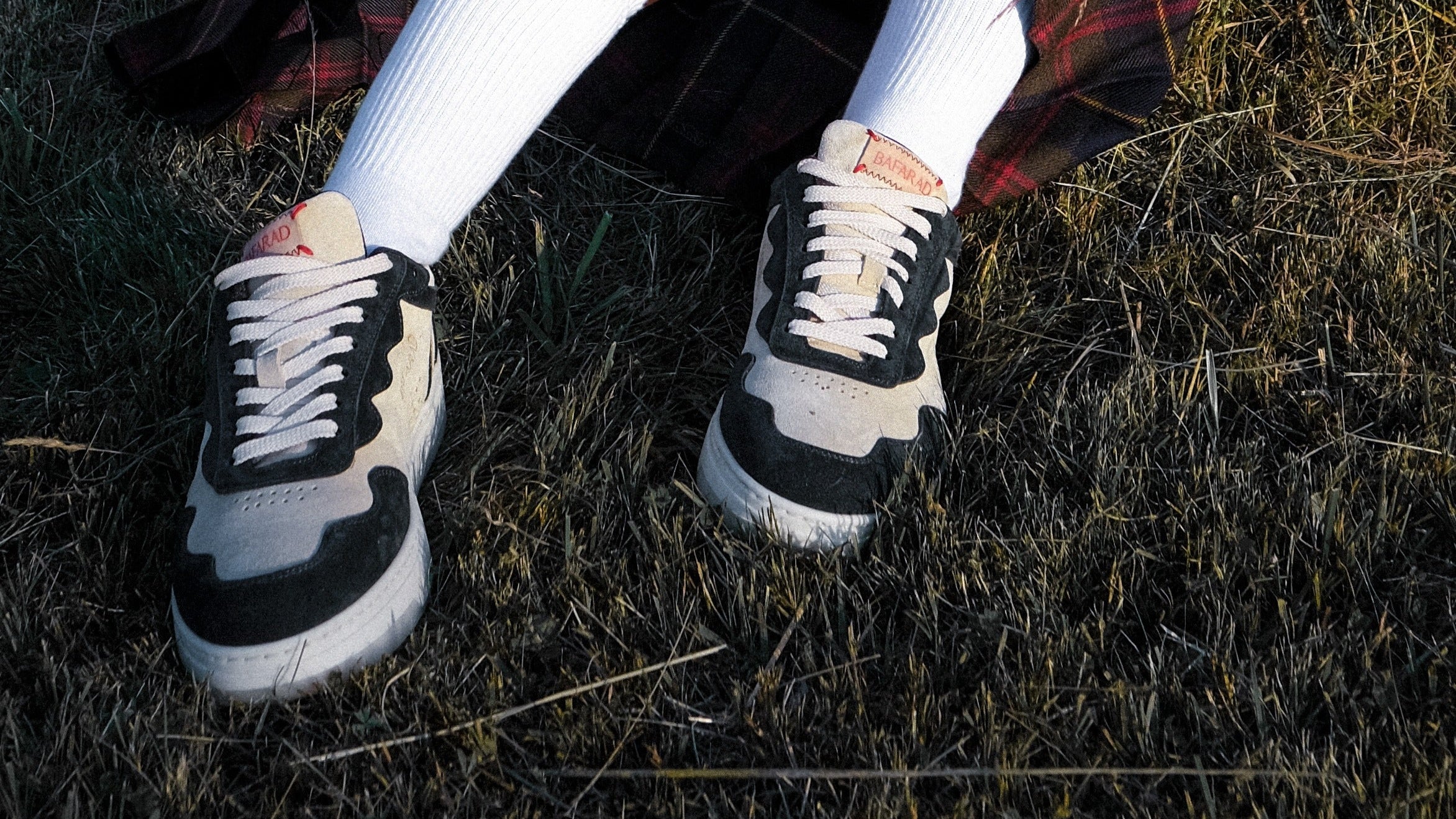 Black and white sneakers worn on grass