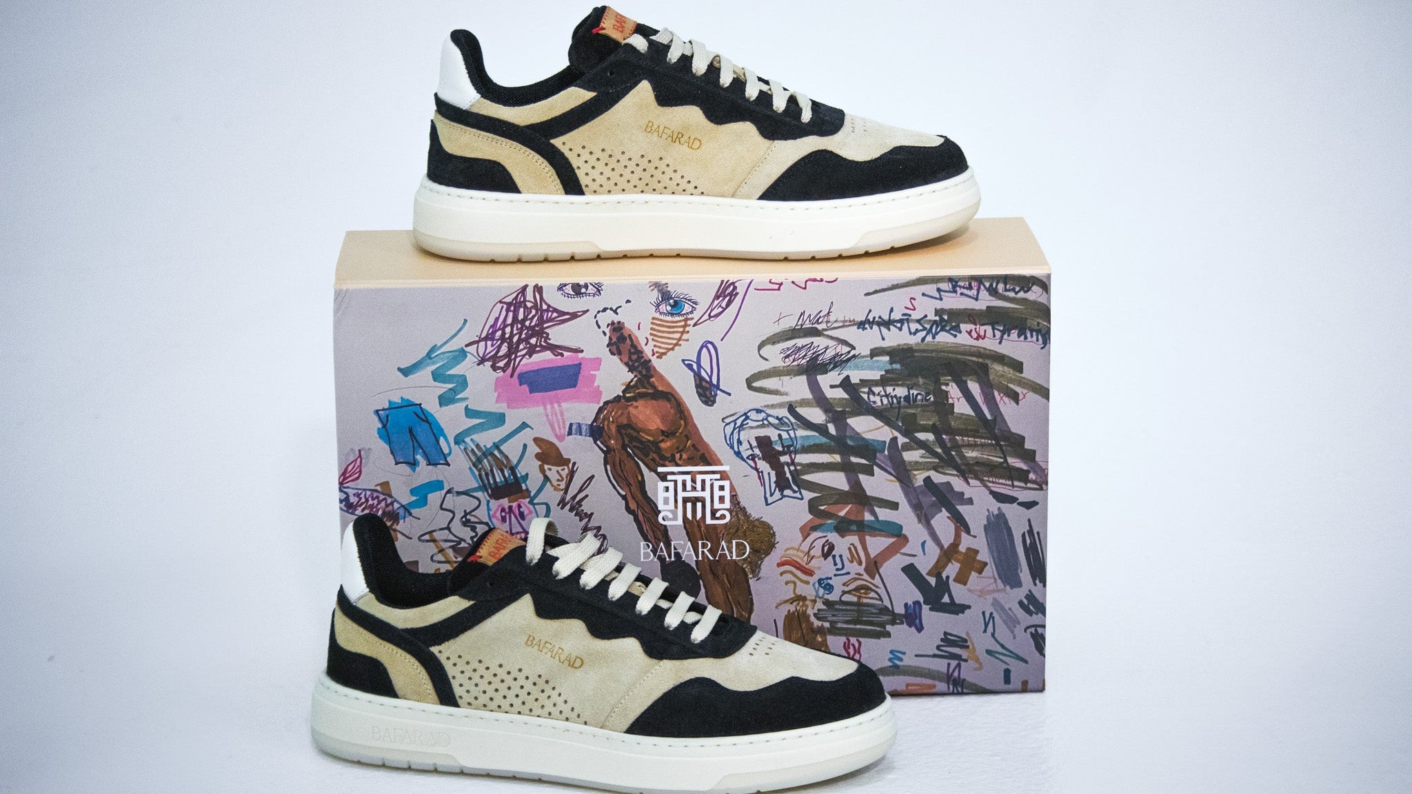 Pair of black and beige sneakers on a colorful box with abstract designs.