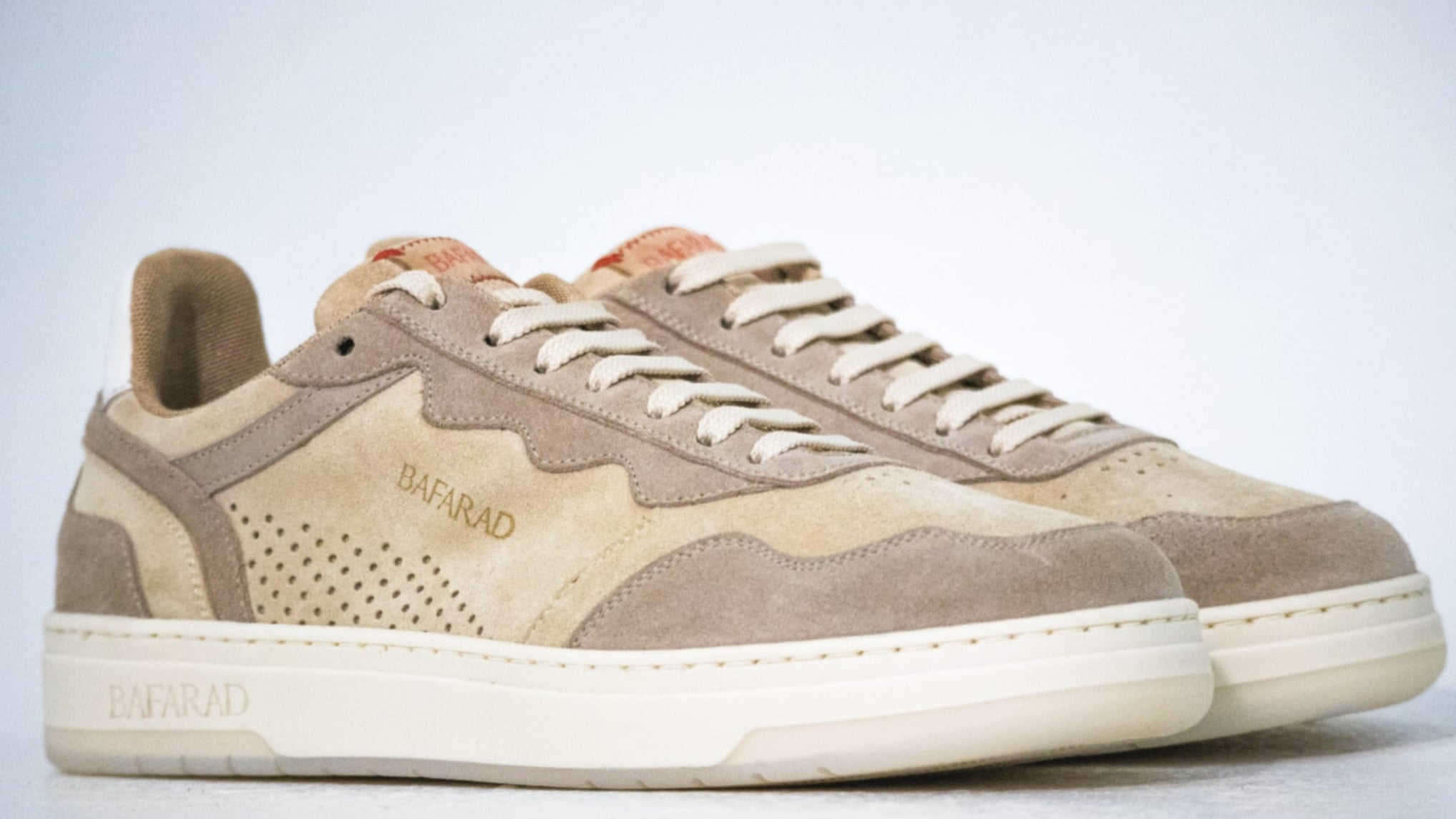 Pair of beige and brown sneakers on a light gray background