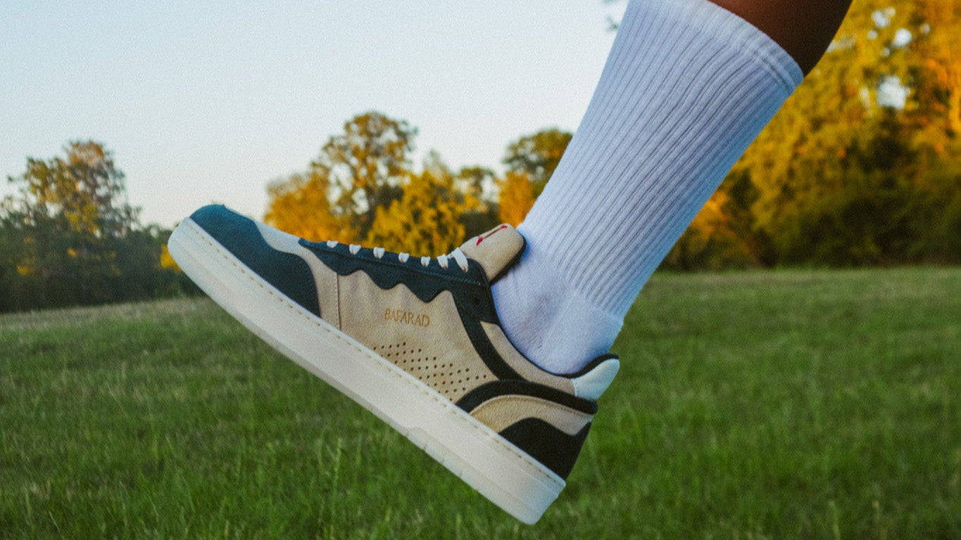 Person wearing a black and white sneaker with a blue accent on grassy field