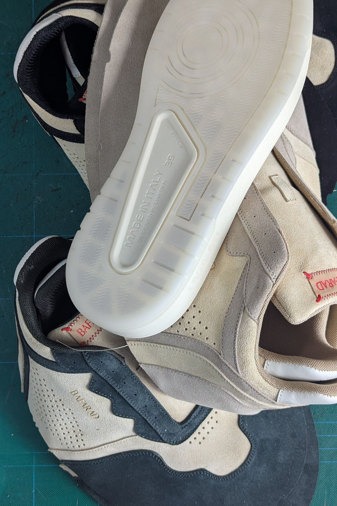 Close-up of a pair of sneakers on a green cutting mat with grid lines.